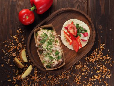 Bir kağıt konteynırı içinde peynir, makarna ve dereotu ile kızarmış domuz