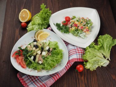 Ahşap bir masada tabaklarda sebze ve otlar ile iki salata