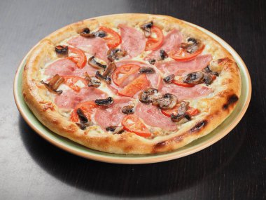 Bir tabakta jambon, domates ve mantar ile Pizza