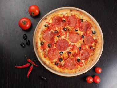 Bir tabakta salam, domates ve zeytin ile Pizza