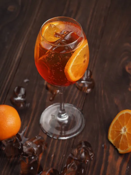 Orange cocktail with ice in a glass on a wooden surface
