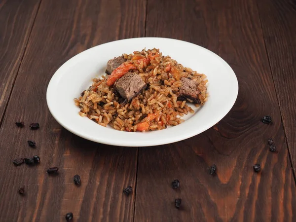 Riz aux légumes et viande dans une assiette sur une table en bois — Photo