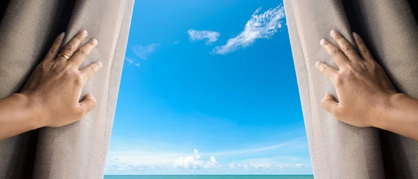 Hope concept . Man opening window curtains and seeing the  blue sky above the sea