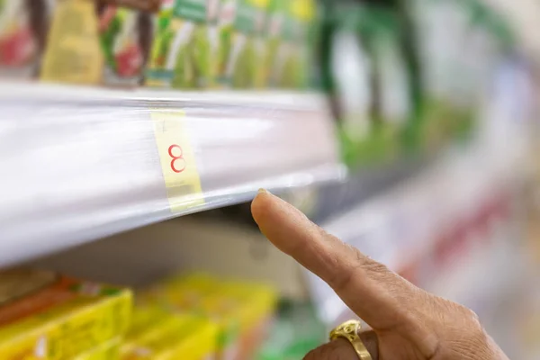 Old customer pointing at best price at supermarket