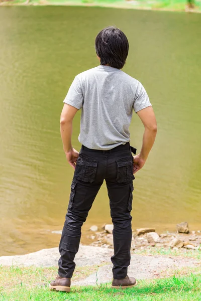 Happy man wearing cargo pants and T-shirt standing beside the river