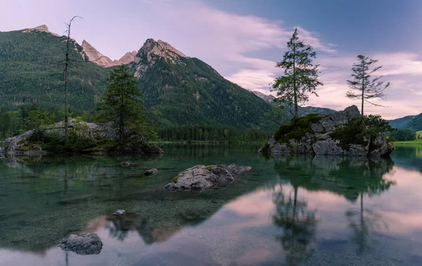 Gyönyörű jelenet fák egy szikla sziget és hegyek naplementekor nyáron, Lake Hintersee Nemzeti Park Berchtesgadener Land, Felső-Bajorország, Németország, Európa Jogdíjmentes Stock Képek