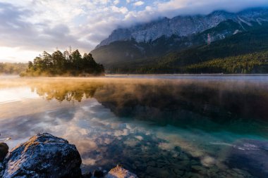 Alman Alpleri 'ndeki Eibsee Gölü' nde güzel ve bulutlu yaz gündoğumu Garmisch-Partenkirchen 'in güneybatısında Bavyera' daki Wetterstein Dağları 'ndaki Zugspitze' nin altında.