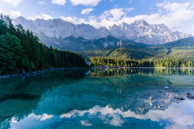 Alman Alpleri 'ndeki Eibsee Gölü' nde güzel ve bulutlu yaz gündoğumu Garmisch-Partenkirchen 'in güneybatısında Bavyera' daki Wetterstein Dağları 'ndaki Zugspitze' nin altında.