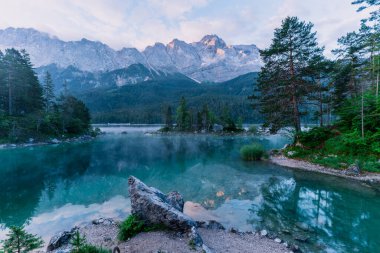 Alman Alpleri 'ndeki Eibsee Gölü' nde güzel ve bulutlu yaz gündoğumu Garmisch-Partenkirchen 'in güneybatısında Bavyera' daki Wetterstein Dağları 'ndaki Zugspitze' nin altında.