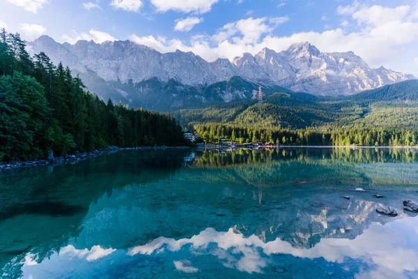 Alman Alpleri 'ndeki Eibsee Gölü' nde güzel ve bulutlu yaz gündoğumu Garmisch-Partenkirchen 'in güneybatısında Bavyera' daki Wetterstein Dağları 'ndaki Zugspitze' nin altında.