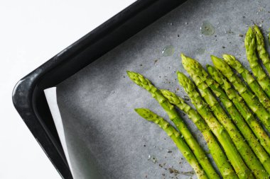 Fırın tepsisindeki yeşil kuşkonmaz. Bir demet taze kuşkonmaz. Sağlıklı organik yiyecekler. Evde yemek pişirmek. Doğal vitaminler, yemek için ham malzeme. Özenle seçilmiş biyolojik kuşkonmaz.