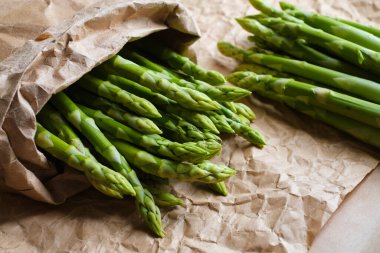 Kraft kağıdında yeşil kuşkonmaz. Bir demet taze kuşkonmaz. Sağlıklı organik yiyecekler. Evde yemek pişirmek. Doğal vitaminler, yemek için ham malzeme. Özenle seçilmiş biyolojik kuşkonmaz.