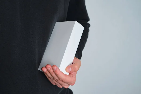 Man holding in hand small paper box. Blank packing, empty space. Male with a new package. Postal service, delivery. White paper. Gift box, present. Box close up. People communication. Carton case