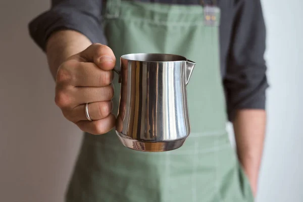 Man hold metal milk pitcher in his hands. Barista milk pitcher closeup. Metal milk jug. Milk frother. Drinks in a cafe. Hot beverage. Equipment for making coffee. Professional coffee service