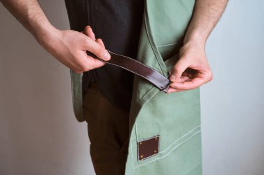 Mutfak önlüklü bir adam. Aşçıbaşı mutfakta çalışıyor. Üniformalı aşçı, koruyucu giysi. Yemek servisinde iş. Profesyonel aşçı. Yeşil kumaş önlük, günlük tarz kıyafetler. İş yerinde poz veren yakışıklı fırıncı