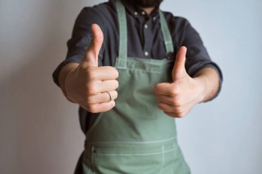 Mutfak önlüklü bir adam. Aşçıbaşı mutfakta çalışıyor. Üniformalı aşçı, koruyucu giysi. Yemek servisinde iş. Profesyonel aşçı. Yeşil kumaş önlük, günlük tarz kıyafetler. İş yerinde poz veren yakışıklı fırıncı