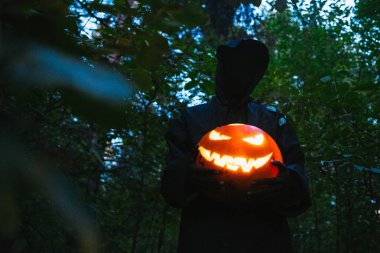 Elinde siyah bir adam Helluin kabak karanlık bir ormanda tutar.