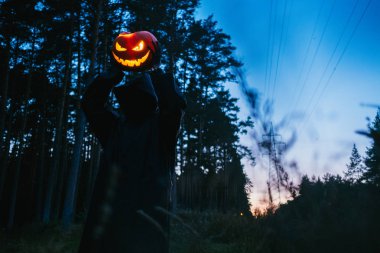 Elinde siyah bir adam Helluin kabak karanlık bir ormanda tutar.