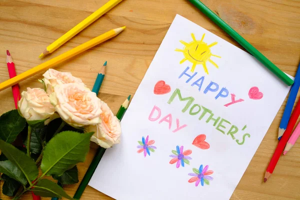 Drawing a pencil for Mother\'s Day on a wooden table with colored pencils