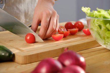 Kız lezzetli bir salata için taze domates keser. Ahşap tabl taze sebze çeşitli