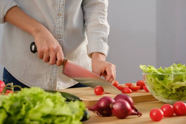 Kız lezzetli bir salata için taze domates keser. Ahşap tabl taze sebze çeşitli