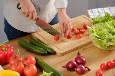 Kız lezzetli bir salata için taze domates keser. Ahşap tabl taze sebze çeşitli