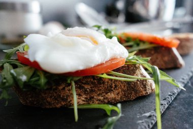 Kepekli ekmek ve haşlanmış yumurta yeşil salata, domates siyah taş tahtası ile sağlıklı bir kahvaltı