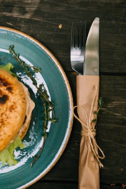 Hamburger ahşap arka plan ve aletleri üzerinde mavi bir tabakta. Lokanta her gün için