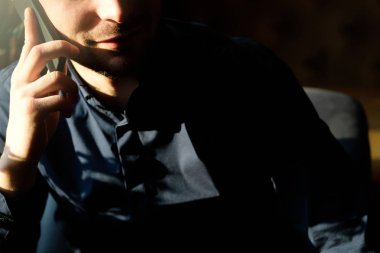 Gölge penceresinde yakınındaki telefonda konuşan işadamı