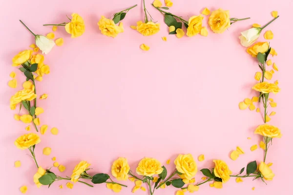 Frame of yellow flowers on a pink background. Top view with copy space.