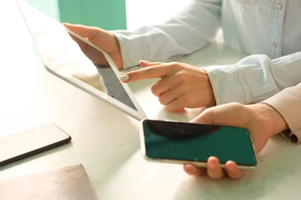 The girl touches the finger of the screen of the tablet, the girl with the phone