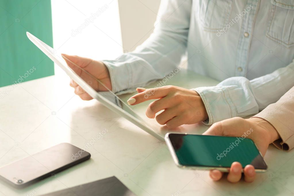 The girl touches the finger of the screen of the tablet, the girl with the phone