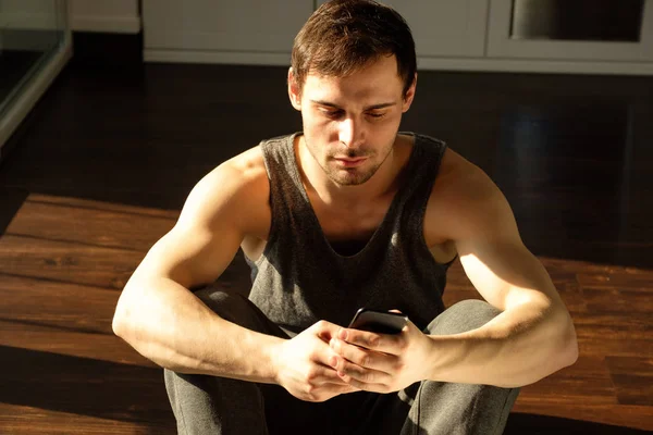 Joven Hombre Guapo Usando Teléfono Mientras Hace Ejercicio Gimnasio Chico — Foto de Stock