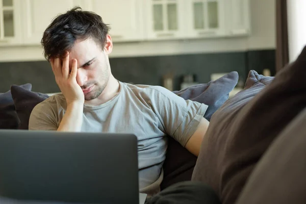 frustrated man in front of a laptop at home on the couch