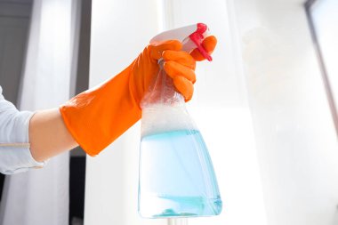 Mavi bir bez ile turuncu eldiven bir cam kız yıkar