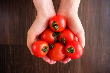 Bir kızın avuç içlerinde birkaç kırmızı domates