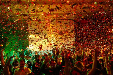 İnsanlar bir partide ellerini havaya kusuyor tavandan konfeti düşüyor