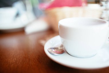 Koyu ahşap bir masada beyaz fincan çay.