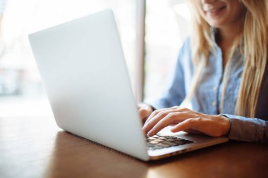 Kafede çalışan genç bir kadın, dizüstü bilgisayarda klavye. Üniversitedeki derslerden sonra netbook için çalışan sarışın bir öğrenci..