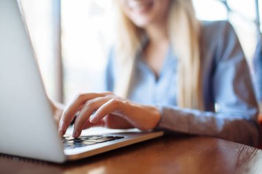 Kafede çalışan genç bir kadın, dizüstü bilgisayarda klavye. Üniversitedeki derslerden sonra netbook için çalışan sarışın bir öğrenci..