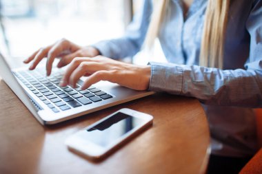 Kafede çalışan genç bir kadın, dizüstü bilgisayarda klavye. Üniversitedeki derslerden sonra netbook için çalışan sarışın bir öğrenci..