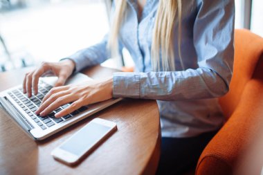 Kafede çalışan genç bir kadın, dizüstü bilgisayarda klavye. Üniversitedeki derslerden sonra netbook için çalışan sarışın bir öğrenci..