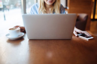 Kafede çalışan genç bir kadın, dizüstü bilgisayarda klavye. Üniversitedeki derslerden sonra netbook için çalışan sarışın bir öğrenci..