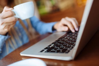 Kafede çalışan genç bir kadın, dizüstü bilgisayarda klavye. Üniversitedeki derslerden sonra netbook için çalışan sarışın bir öğrenci..