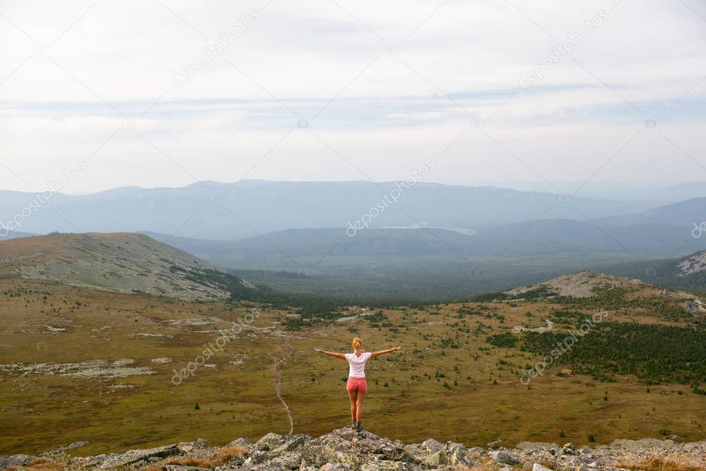 Tourist girl traveler admiring the view of the mountains