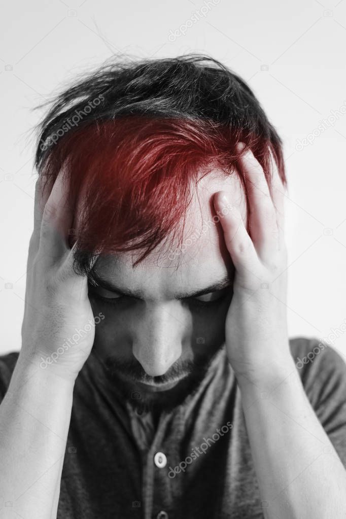 A fit man holding his head in pain, on a white background. Place of pain red dot