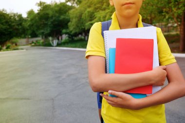 Bir çocuğun elinde ki kitaplar ve defterler