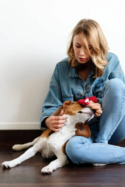 Girl in a sweater at home plays with a dog