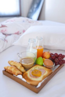 Kahve, kruvasan pencere ışık ile yatakta kahvaltı