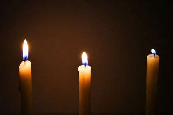 White Candles Burning in the Dark with lights glow, the burning candle\'s flame in the dark background, a symbol of the Christian faith, Candles burning in the Dark with lights glow